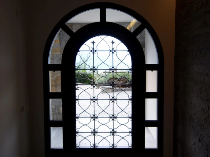 Porta ad arco con vetri e griglia metallica decorativa – Giugni SA